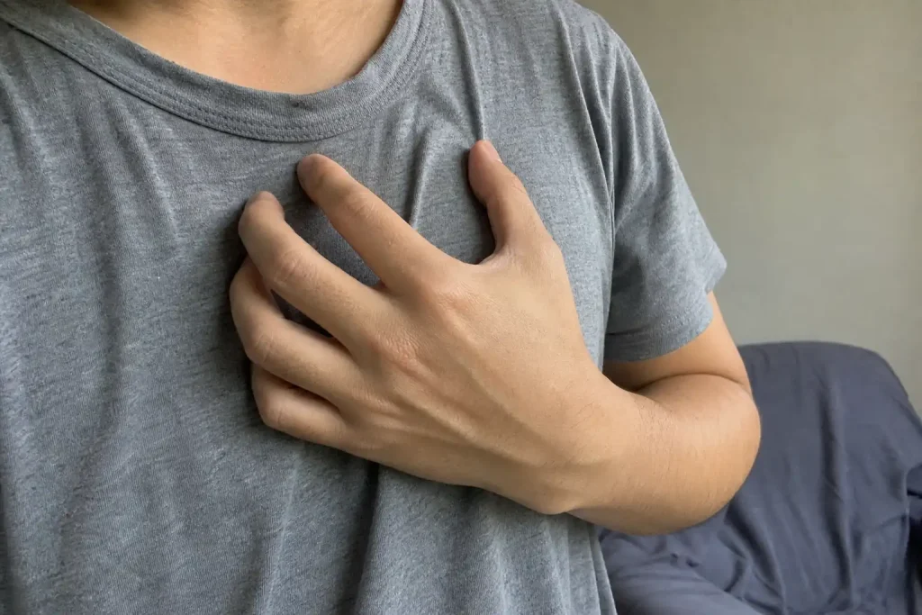 En hand vilar mot bröstet nära nyckelbenet, en vardagsbild kopplad till blodsockermätare för friska.