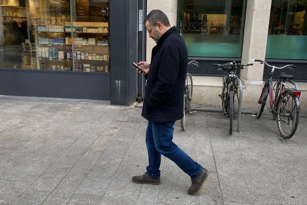 Medelålders man läser på mobilen utanför apoteket på väg hem, en vardagsbild kopplad till tirzepatid hjärt-kärlrisk diabetes.